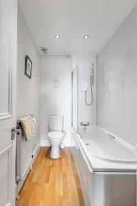 a white bathroom with a tub and a toilet at Above The Bay in Port Bannatyne