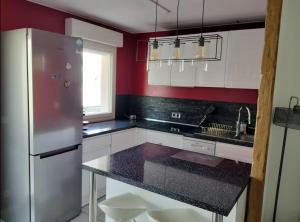 een keuken met een roestvrijstalen koelkast en rode muren bij Appartement avec parking privé in Aytré +4 foto's