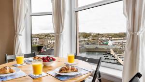 a table with food and orange juice and a large window at Lady Mary Sea View in Rothesay