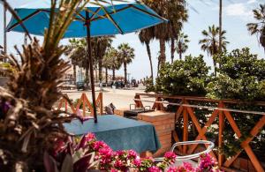 a table and chairs with a blue umbrella and palm trees at Bungalows Cerro Azul in Cerro Azul