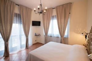 a bedroom with a white bed with curtains and a chandelier at Villa Bordone in Tigliole