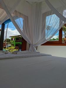 a bed with a white canopy and a window at Casa Villa Cristian Pé na Areia in Arraial d'Ajuda +72 photos