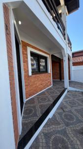 ein Balkon eines Hauses mit Fenster und Fliesenboden in der Unterkunft Prudêncio Casas de Temporada in Torres