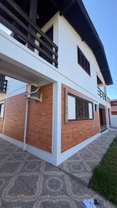 ein weiß-rotes Backsteingebäude mit einem Balkon in der Unterkunft Prudêncio Casas de Temporada in Torres