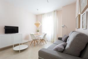 uma sala de estar com um sofá e uma mesa em Apartamentos Diaber San Leandro em Sevilha