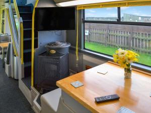 een tafel met een vaas met bloemen en een televisie bij Daisy Decker - Uk48371 in Hollym