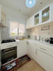 a kitchen with white cabinets and a stove and a window at Résidence Bethel in Libreville
