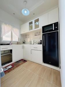 a kitchen with white cabinets and a black refrigerator at Résidence Bethel in Libreville +4 photos