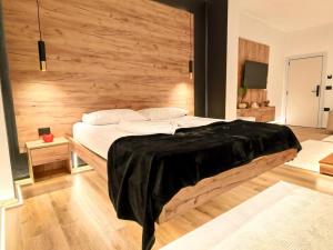 a bedroom with a large bed with a wooden wall at Jacuzzi Studio Room in Shkodër +8 photos