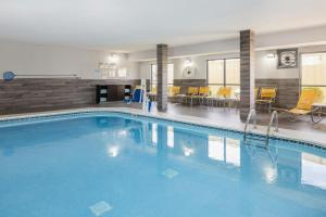 a large pool in a hotel with chairs and tables at Fairfield by Marriott Inn & Suites Grand Rapids Airport in Grand Rapids