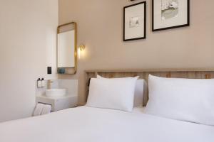 a bedroom with two white beds and a sink at The Drey - Kensington, Earl's Court in London