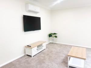 a room with a table and a tv on a wall at Eliza's Escape 2 Wagga CBD in Wagga Wagga