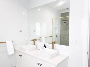a white bathroom with two sinks and a shower at Eliza's Escape 2 Wagga CBD in Wagga Wagga +28 photos