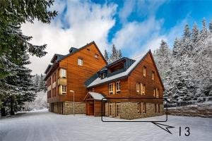 a large wooden house in the snow at Horní Mísečky - I3 Pohodlný a teplý apartmán u sjezdovky in Horni Misecky