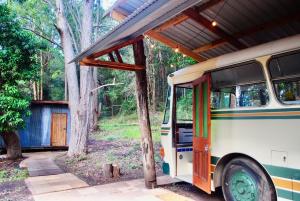 an old bus parked under a building in the woods at Coffee Grounds - The Coach in Coffee Camp