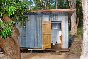 a corrugated metal bathroom with a toilet in a shed at Coffee Grounds - The Coach in Coffee Camp
