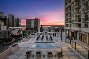 Courtyard by Marriott San Diego Downtown Little Italy في سان دييغو: مسبح على السطح مع كراسي ومظلات على مبنى