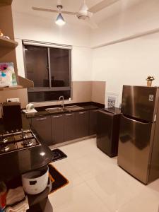 a kitchen with black cabinets and a stainless steel refrigerator at Bright 3-Bed Flat with Balcony with Great Value in Sri Jayewardenepura Kotte