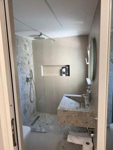 Un baño con ducha, lavabo y bañera. en TheCozy Home Tirana, en Sauk