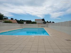a swimming pool with a tile floor and a wall at Charmante Maison Bord de Mer avec Piscine et Tennis 5-P in Saint-Vincent-sur-Jard