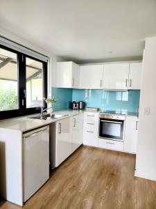 cocina con armarios blancos y paredes azules en Cozy Getaway with private backyard, en Penrith 2 fotos más