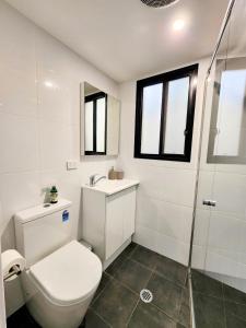 Un baño blanco con inodoro y ducha. en Cozy Getaway with private backyard, en Penrith