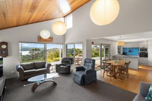 een woonkamer met stoelen en een tafel en een keuken bij Mangonui Ridge Retreat in Mangonui