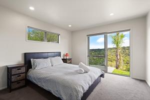 een slaapkamer met een bed en een groot raam bij Mangonui Ridge Retreat in Mangonui