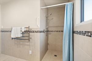 een douche met een blauw gordijn in de badkamer bij Mangonui Ridge Retreat in Mangonui +16 foto's