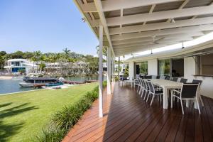 eine Außenterrasse mit Tisch und Stühlen am Wasser in der Unterkunft 21 Wesley Court Noosa Sound in Noosa Heads