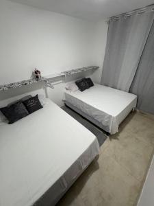zwei Betten in einem Zimmer mit weißen Wänden in der Unterkunft Casa em Angra dos Reis, no parque mambucaba in Angra dos Reis