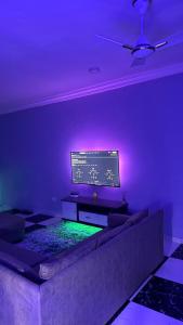 a living room with a couch and a tv with purple lights at Cozy 2-bedrooms in Lakeside Estate Accra in Apenkwa