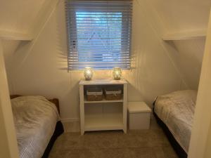 a small bedroom with two beds and a window at Boshuisje Rekem Charly in Lanaken