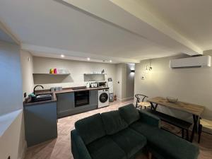 Una sala de estar con un sofá verde y una cocina. en Akroyd House - The Dean Clough Room, en Halifax
