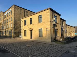 un viejo edificio de ladrillo al lado de una calle en Akroyd House - The Dean Clough Room, en Halifax