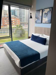 a bedroom with a bed with a large window at UniqueMine Apartamento Deluxe in Bogotá