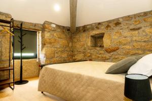 a bedroom with a large bed in a stone wall at Quinta dos Castanheiros in Oliveira de Frades +19 photos