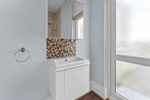 a white bathroom with a sink and a window at The Royal Stay at Queens Hill Sleeps 10 in Newport +30 photos