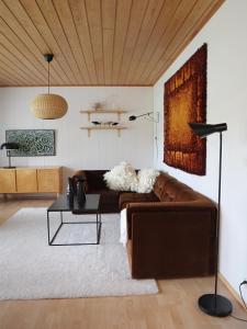 a living room with a brown couch and a table at Villa Vintage, Scandinavian Design and Comfort Near the City and Ski Slopes in Rovaniemi