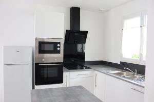a white kitchen with black appliances and a sink at Relaxing, quiet, private spa, Besançon in Émagny