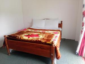 ein kleines Bett in einem Zimmer mit einer Bettdecke darauf in der Unterkunft Villa Serenity Heights in Nuwara Eliya