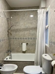 a bathroom with a tub and a toilet and a sink at La Vega Rooms in Huelva