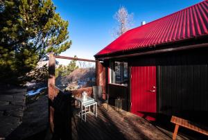 a red cabin with a table on the porch at Cheerful forest cabin Fireplace and Hot tub in Akranes