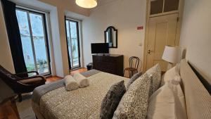 a bedroom with a bed and a chair and windows at Costa do Castelo Lisbon Accomodation in Lisbon