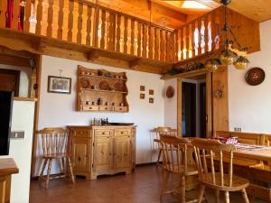 una cocina con armarios de madera y un bar con sillas en Mansarda Veronza, en Castello di Fiemme