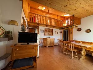 Una sala de estar con un televisor y una mesa con sillas. en Mansarda Veronza, en Castello di Fiemme