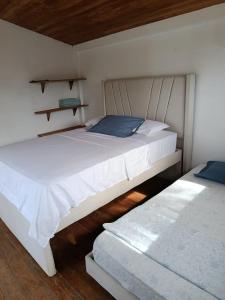 two beds in a room with white walls and wooden floors at cabañas Brisas y Perla by AMAUNA in Moñitos