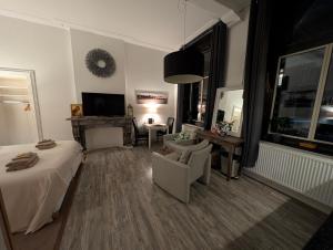 Un dormitorio con una cama y una silla y un televisor. en Klooster Mariadal Maastricht, en Maastricht