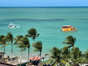 two boats in the ocean with palm trees on the beach at Verão João Pessoa-apto inteiro-2 quartos in Cabedelo