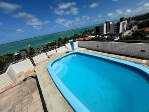 a swimming pool with the ocean in the background at Verão João Pessoa-apto inteiro-2 quartos in Cabedelo